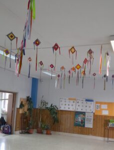 l'immagine è una foto di una sala interna della scuola primaria di cavour, con appesi sul soffitto degli aquiloni di carta piccoli