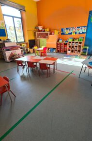 aula con banchi bianchi e rossi, e pareti gialle ed arangioni della scuola dell'infanzia di cavour