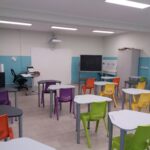 aula della scuola secondaria di primo grado di villafranca con lavagna interattiva, pareti bianche e azzurre e banchi con sedie di vari colori