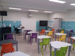 aula della scuola secondaria di primo grado di villafranca con lavagna interattiva, pareti bianche e azzurre e banchi con sedie di vari colori