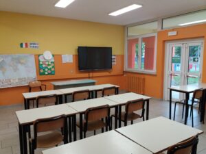 aula della scuola secondaria di primo grado di villafranca con lavagna interattiva, pareti gialle ed arancioni e banchi con sedie di vari colori